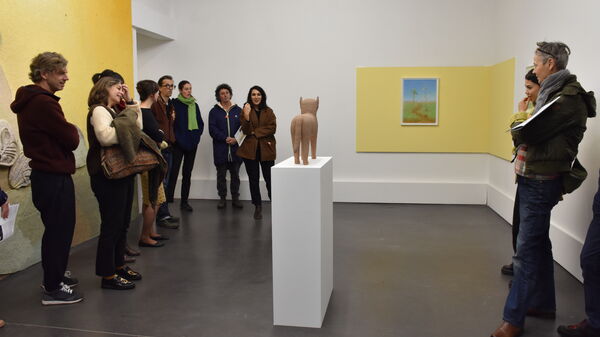 Une dizaine de personnes regarde *Miaou*, un félin en céramique. C'est une des trois œuvres de Corentin Grossmann présentée dans la première salle de la grande galerie, dédiée au camouflage.